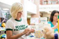 A person in a Mason Patriot shirt preparing items for University Life's Summer Day of Service.