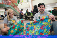 Two students hold up patterned cloth printed with cats and dogs for University Life's Summer Day of Service.